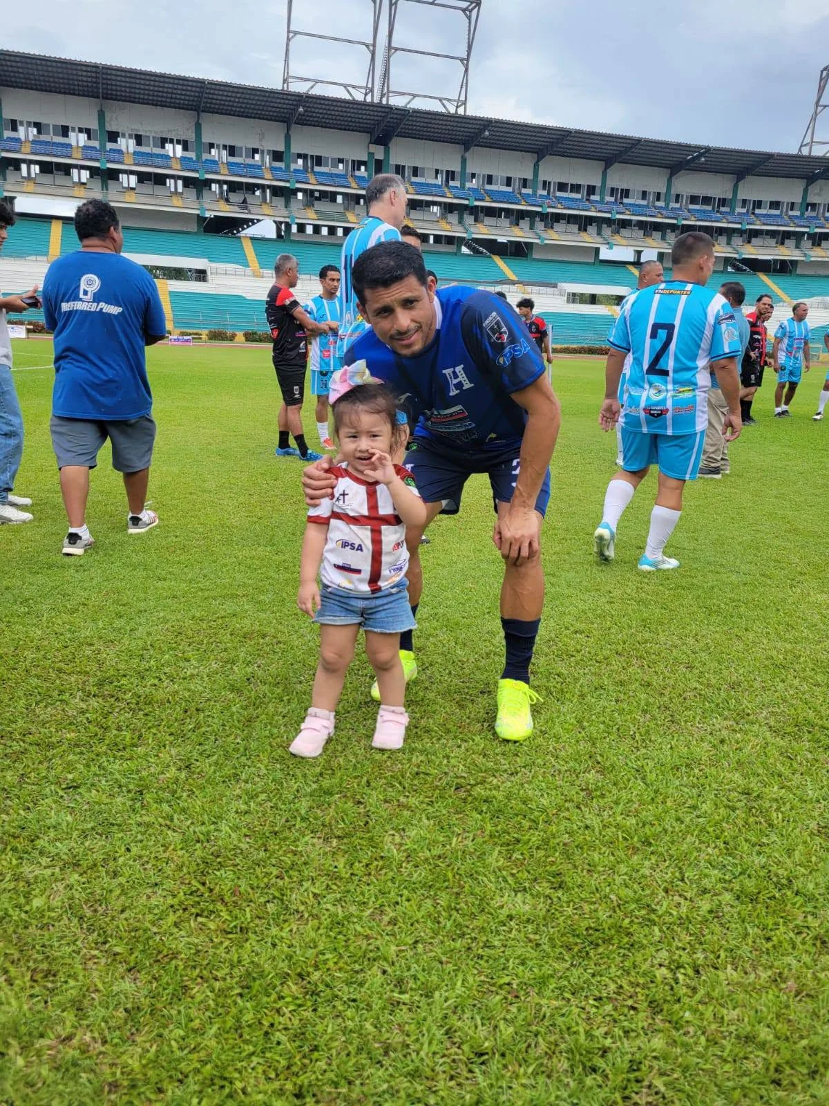 Una niña y un futbolista comparten una sonrisa en la cancha