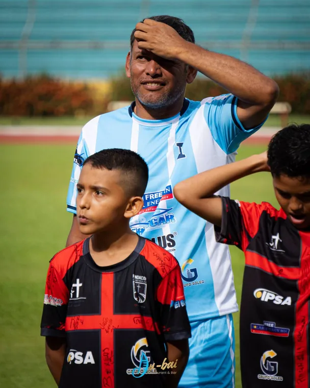 Niños con camisetas de la fundación junto a un futbolista