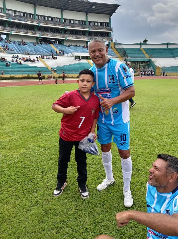 Niño y futbolista posando juntos sobre la cancha