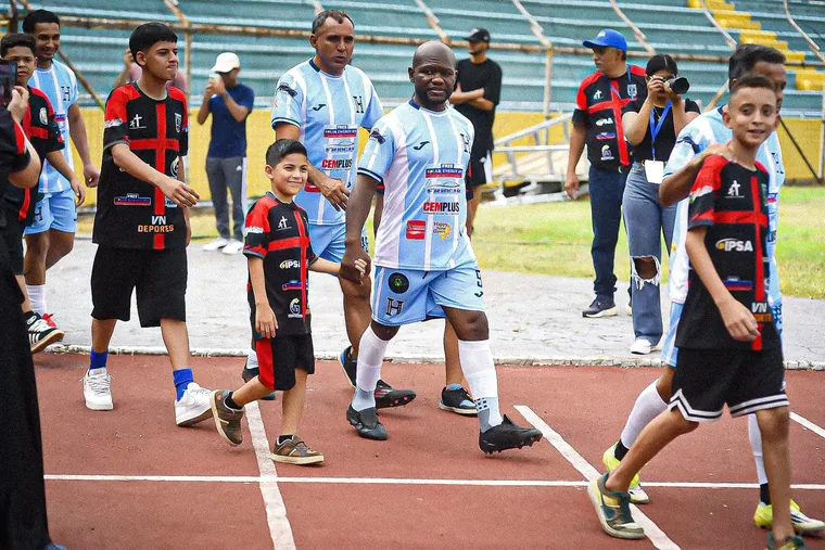 Niños y futbolistas caminando juntos por la pista del estadio