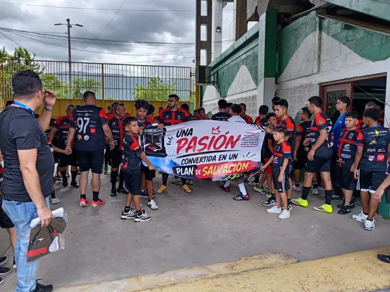 Integrantes de la fundación sosteniendo una pancarta en el estadio