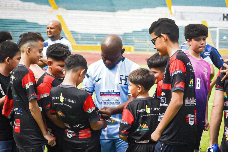 Niños de la fundación reunidos alrededor de un futbolista