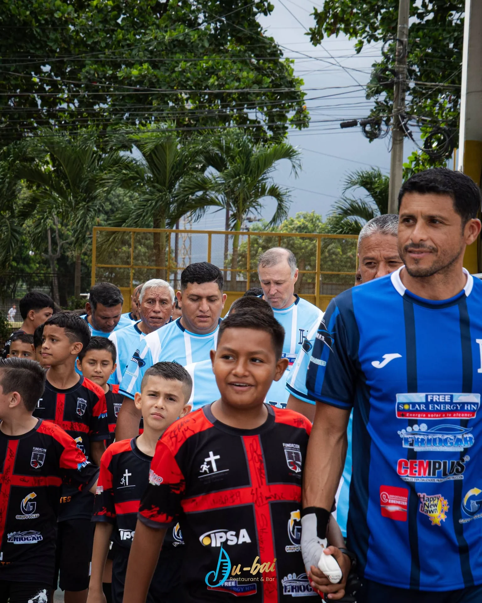 Niño de la fundación caminando de la mano de un futbolista