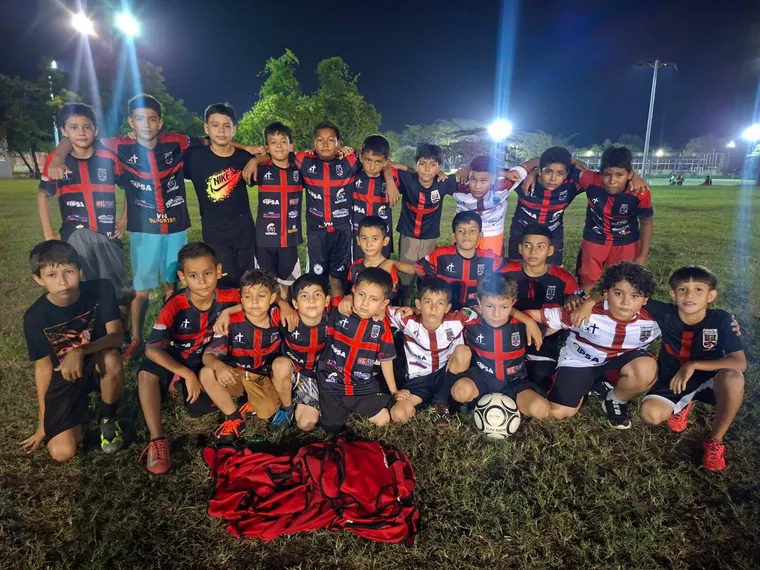 Equipo infantil de la fundación posando en la cancha por la noche