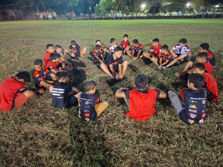 Niños sentados en círculo durante una reunión nocturna en la cancha