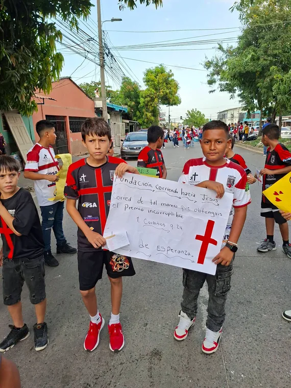Niños sosteniendo una pancarta de la fundación durante una caminata
